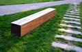 Bench one piece of wood made prism park painted brown footsteps concrete rectangles gray in the lawn and trees Royalty Free Stock Photo