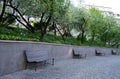 Wooden bench near the edge of the path in the park pedestrian blocks pavement retaining wall low metal frame benches elegant shape Royalty Free Stock Photo