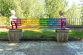Bench for people to sit on painted in rainbow colors for gay pride day on the promenade near a river fence with selective focus Royalty Free Stock Photo