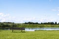 Bench by the river bank with scenic view on green summer idyll nature. Rural landscape with bench