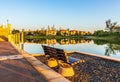 Bench on the shore of the lake with the reflections of buildings and trees in Dubai, UAE Royalty Free Stock Photo
