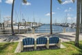 Bench on a sidewalk pathway facing the views of the boats at the marina docks in Miami, Florida bay