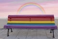 A bench in the street with the colors of the rainbow, symbol of the LGBT community, and an amazing sky in the background Royalty Free Stock Photo