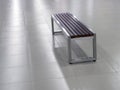 Bench with steel frame and wooden seat elements on the tile floor Royalty Free Stock Photo