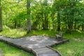 Bench by a wooden footpath with a wooden platform in a nature reserve Royalty Free Stock Photo