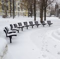 Benches Covered in Snow near Yellow Building in Winter Royalty Free Stock Photo