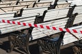 Benches in a public park are in preparation for the coming summer season. The caution tape warns people that benches are still di