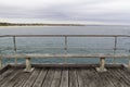 Benches and seats on Port Noarlunga Jetty with beach in background. Royalty Free Stock Photo