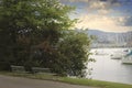 Benches on the side of a road with a view of a lake with boats Royalty Free Stock Photo