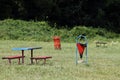 Benches and a trash bin in the grass outside in nature