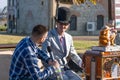 Organ grinder in a hat and round glasses gives an interview on an autumn sunny day in the