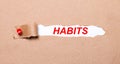 Beneath the torn strip of kraft paper attached with a red button is a white paper HABITS