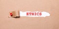 Beneath the torn strip of kraft paper attached with a red button is a white paper labeled ETHICS Royalty Free Stock Photo