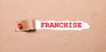 Beneath the torn strip of kraft paper attached with a red button is a white paper labeled FRANCHISE Royalty Free Stock Photo