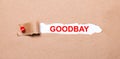 Beneath the torn strip of kraft paper attached with a red button is a white paper labeled GOODBAY Royalty Free Stock Photo