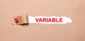 Beneath the torn strip of kraft paper attached with a red button is a white paper labeled VARIABLE Royalty Free Stock Photo