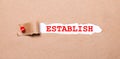 Beneath the torn strip of kraft paper attached with a red button is a white paper ESTABLISH
