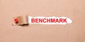 Beneath the torn strip of kraft paper attached with a red button is a white paper labeled BENCHMARK