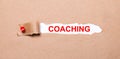 Beneath the torn strip of kraft paper attached with a red button is a white paper labeled COACHING Royalty Free Stock Photo