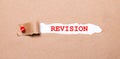 Beneath the torn strip of kraft paper attached with a red button is a white paper labeled REVISION Royalty Free Stock Photo