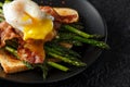 Benedict poached Duck egg with crispy bacon and fried asparagus on toasts for breakfast