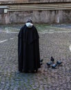 Benedictine monk feeding pigeons on the street, Rome, Italy