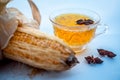 Beneficial detoxifying corn tea in a glass cup isolated on white along with some Star anise spice.Raw corn cob also present