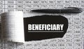 BENEFICIARY is the word behind torn office paper with numbers and a black pen