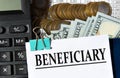 BENEFICIARY - word on a white sheet against the background of a calculator, banknotes and pennies