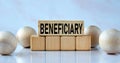 BENEFICIARY - word on wooden cubes on a light background with balls