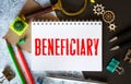 BENEFICIARY word is written in a notebook with a marker, calculator, clamps and cactus