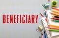 BENEFICIARY word is written in a notebook with a marker, calculator, clamps and cactus