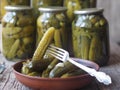 The benefits and harms of canned pickled cucumbers. Pickled cucumbers on a fork and in cans on a wooden ancient background. Side Royalty Free Stock Photo