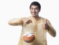 Bengali man carrying a pot of rasgulla and showing thumbs up sign