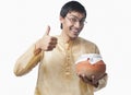 Bengali man holding a pot of rasgulla and showing thumbs up sign