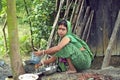 Bengali woman during dish washing outside poor hut