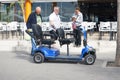 Benidorm, Spain - Holiday makers and disability scooter in Benidorm city nea outdoors cafe