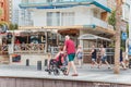 Tourists walking along the seafront of Levante beach in cloudy September weather, an elderly man carries