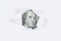 Benjamin Franklin macro peeking through torn white paper.