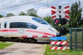 Bennekom-Netherlands,Juli 11,2020:German ICE train passing a closed railway crossing with closed barriers blinking red