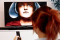 Benon, France - December 30, 2018: Woman Holding a TV remote and watch The Handmaid`s Tale. The Handmaid`s Tale is a futuristic