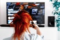 Redhead woman sitting in her living room Holding a TV remote control and displays the netflix Royalty Free Stock Photo