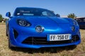 blue new Renault Alpine A110 car exhibited at the tour de france in small village contryside