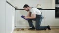 Bent caucasian man making routine plumbing analysis in light apartment