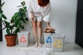 Bent forward woman stuffing piece of crampled packing paper in small recycle bin Royalty Free Stock Photo