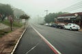 Street with houses and parked cars on a foggy day