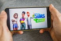 Berdyansk, Ukraine - March 4, 2019 - Close up of hand of person playing The Sims Mobile game apllication Royalty Free Stock Photo