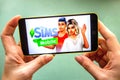 Berdyansk, Ukraine - March 4, 2019 - Close up of hand of person playing The Sims Mobile game apllication Royalty Free Stock Photo