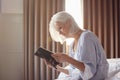 Bereaved Senior Woman Sitting On Edge Of Bed Looking At Photo In Frame Royalty Free Stock Photo