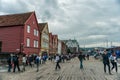 Bergen, Norway-July 30, 2013: photo of the wooden promenade of Bergen on a cloudy day. People walk along the waterfront